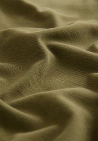 Õlivihre kangas, millel on pehme ja tekstuuriga pind, kus on nähtavad õrnad voldid ja kortsud, mis näitavad selle langevust ja paindlikkust.