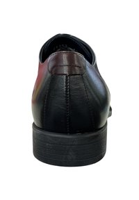 Zapato de cuero negro con un tacón redondeado, textura suave y un acento burdeos contrastante en la parte trasera. Presenta costuras limpias y una suela sólida.