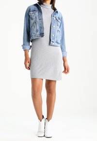 Jeansjacka, ljusblå, kort design, knäppning med knappar, kombinerad med en grå polotröja klänning, knälång, slät textur; vita ankelboots.