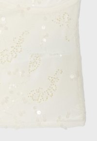 Tissu blanc transparent avec des détails délicats de broderies florales en perles et paillettes sur un vêtement sans manches.