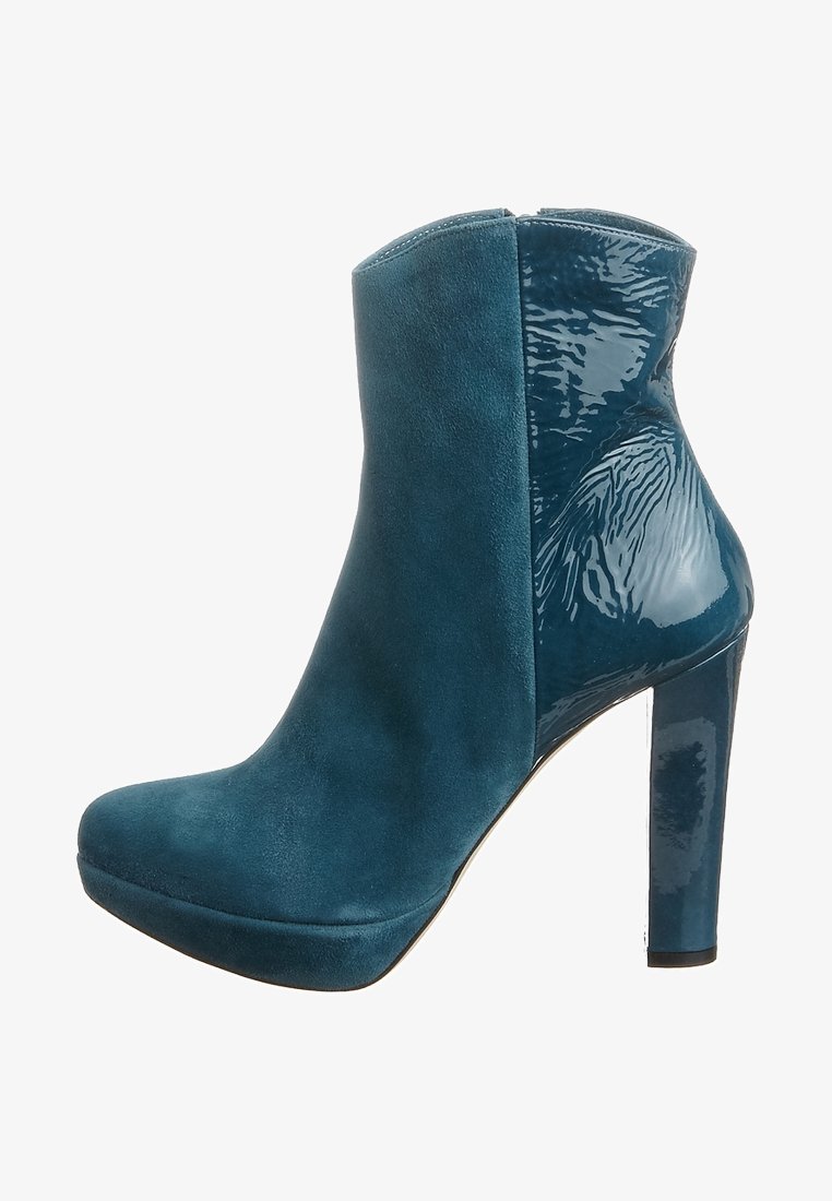 Teal ankle boot featuring a mix of matte suede and glossy patent materials, with a slender high heel and rounded toe design.