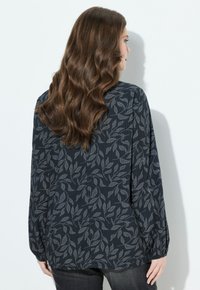 Langsleeve blouse in diep marineblauw met een lichtgrijs bladerenpatroon, textuurstof, losse pasvorm, verzamelde manchetten en subtiele halslijn detail.