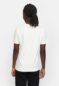 Weißes Baumwoll-T-Shirt mit kurzen Ärmeln und Rundhalsausschnitt, mit einer glatten Textur und schlichten Nähten auf dem Rücken.