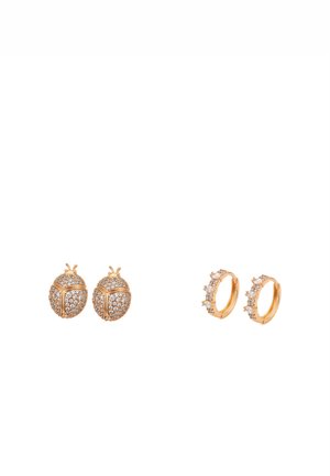 To par øreringe i guld på hvid baggrund: et par mariehønsformede med krystaller og et par små creoler med krystalklynger langs den ydre kant.