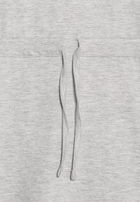 Jasnoszara tkanina bluzy z kapturem, z przednią kieszenią i dwoma sznurkami. Tekstura jest miękka i gładka, o prostym wzorze.