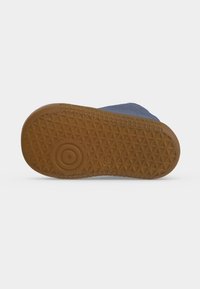 Semelle d'une chaussure bleue avec une semelle en caoutchouc marron affichant des motifs circulaires et triangulaires sur fond blanc.