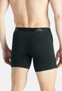 Zwarte boxershorts voor heren met een gladde textuur en een elastische tailleband met drie horizontale strepen. Strakke pasvorm.