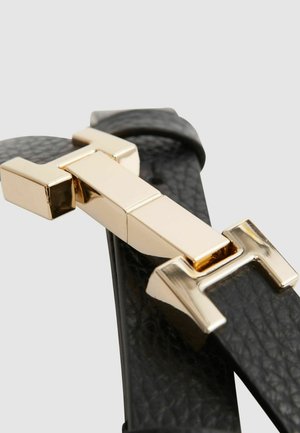 Cintura in pelle nera con una fibbia geometrica in tonalità oro. La fibbia ha una finitura lucida con forme rettangolari e bordi lisci.