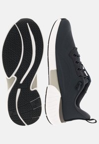 Dunkle Netz-Laufschuhe mit einer weißen, wellenförmigen Sohle, gerundetem Absatz und grauen Akzenten. Schnürsenkel und minimale Polsterung sind vorhanden.
