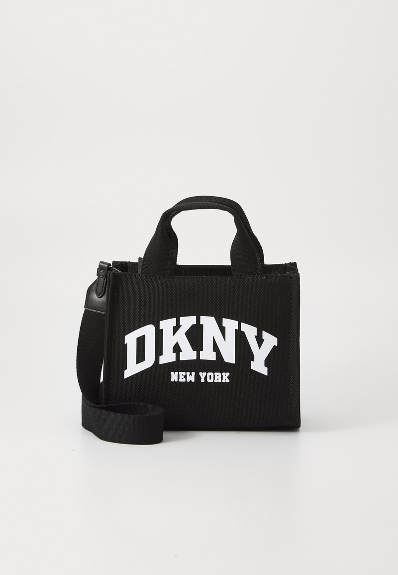 Black fabric handbag with white "DKNY NEW YORK" logo. Features dual handles and a detachable strap. Rectangular shape with textured surface.