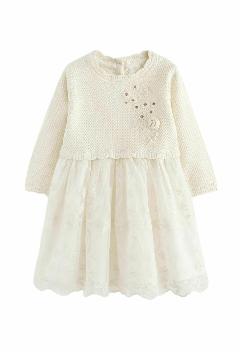 Robe de bébé couleur crème avec haut en maille à manches longues et jupe en dentelle florale, décorée de petites fleurs en tissu sur la poitrine.