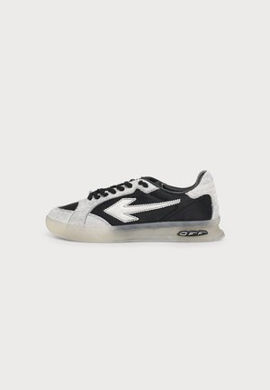 Zapatilla blanca y negra con diseño de flecha blanca en el lateral, cordones negros, ribete blanco texturizado y suela translúcida con detalle de texto "OFF".