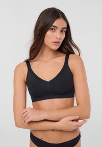 Bralette nero senza cuciture con design a V, spalline larghe e texture morbida. Adatto per abbigliamento casual e per stratificazione.