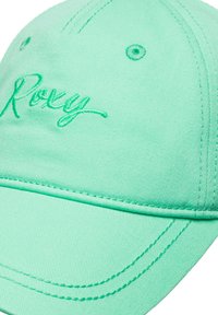 Mint green cap made of textured fabric with a curved brim, featuring embroidered "Roxy" logo in matching thread and visible stitching details.