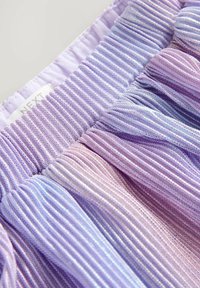 Flerfärgad plisserad tyg med nyanser av lila och lavendel. Materialet är lättviktigt med en mjuk textur. Etiketten säger "NEXT."