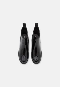 Černé nízké boty z lakované kůže s elegantním designem, elastickými bočními panely a poutky pro snadné nazouvání. Hladký, lesklý povrch.