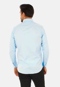 Camicia azzurra a maniche lunghe in cotone, con colletto classico e polsini abbottonati, caratterizzata da una texture liscia e una vestibilità sagomata.