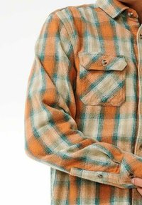 Camicia di flanella a quadri arancione e teal con due tasche sul petto e chiusura con bottoni. Presenta un tessuto testurizzato, una vestibilità comoda e maniche arrotolate.