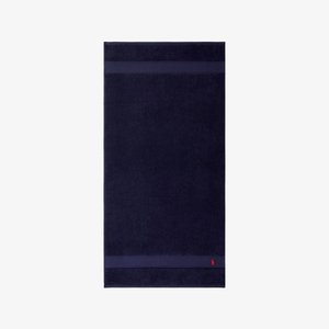 Toalla de baño azul marino con una textura suave, que presenta dos franjas horizontales y un pequeño logo bordado en rojo en el borde inferior.