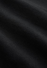 Mustast kangast, tekstuurse pinnaga, millel on peened lainetused, sile kude ja kerge läige, mis annab pehme ja tiheda välimuse.