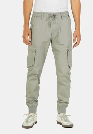 Pantalones cargo verde claro con cintura elástica y cordón, con bolsillos laterales y puños elásticos en los tobillos.