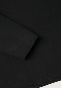 Pull noir avec une texture en maille lisse, un poignet ajusté et un ourlet net, mettant en avant des détails de design simples et minimalistes.