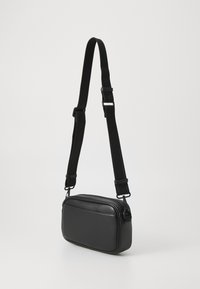 Black crossbody bag made of synthetic leather, featuring a rectangular shape, a zippered closure, and an adjustable fabric strap.