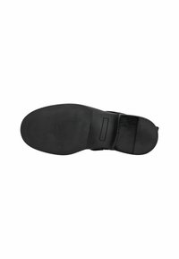 Suela de zapato de goma negra con un patrón de agarre texturizado, un tacón plano y una superficie lisa con un pequeño acento rectangular.