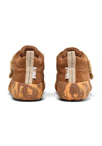 Zapatos marrones para niños pequeños con suelas texturizadas en tonos marrón-naranja, lengüetas para tirar y un pequeño logo de mono en la parte trasera y en las etiquetas de tela laterales.