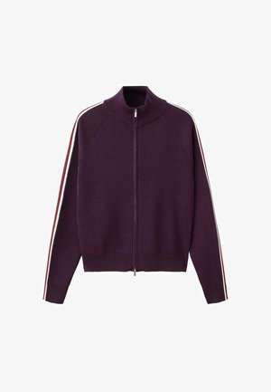 Vijoličen pulover z zadrgo, visokim ovratnikom in rdečimi ter belimi črtami, ki potekajo po celotnih obeh rokavih.