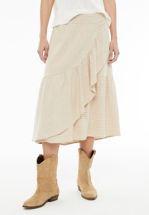 Falda midi a rayas beige con un dobladillo con volantes, que presenta una cintura ajustada y una silueta fluida. Combinada con botas vaqueras marrones.