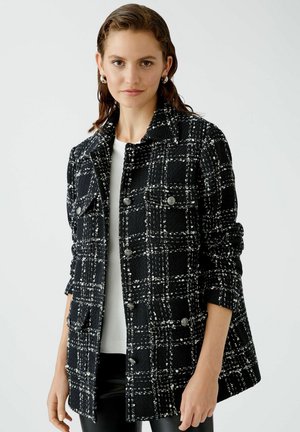 Black and white checkered jacket made of textured fabric, featuring silver buttons and two front pockets, with rolled sleeves and a collar.