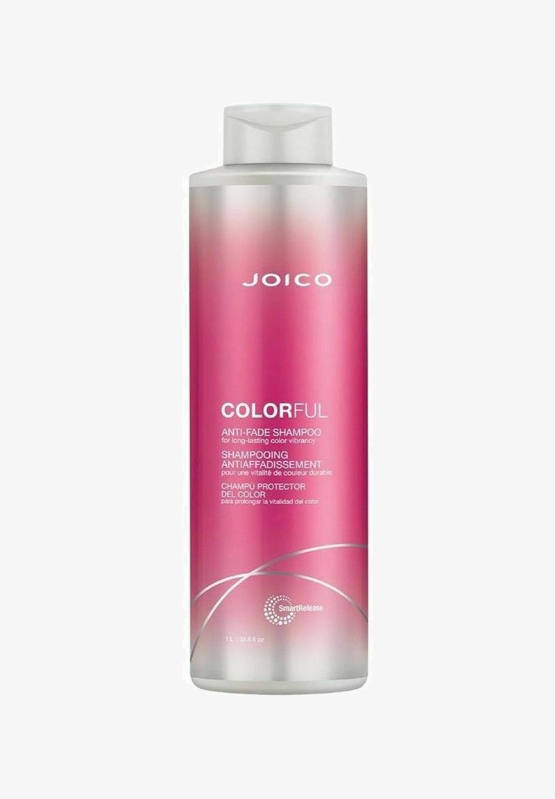 Lyserød plastflaske med JOICO Colorful anti-fade shampoo med hvid flip-top låg og sølvdetaljer, mærket på flere sprog.