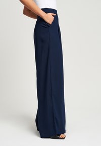 Mornarske široke hlače napravljene od lagane tkanine s bočnim školjcama i visokim strukom, upotpunjene ravnim siluetom.