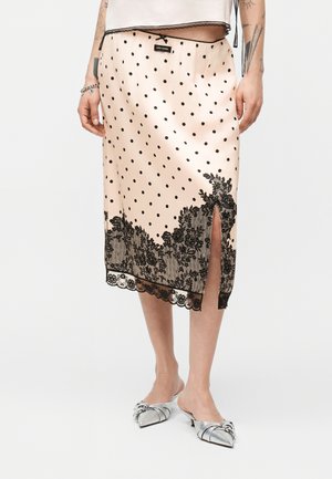 Gonna midi in satin beige con pois neri, bordo in pizzo nero floreale, spacco frontale, indossata con mule con tacco a punta argento.