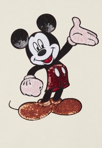 Design ricamato di Mickey Mouse con paillettes rosse e nere su uno sfondo chiaro, con scarpe sovradimensionate e una posa allegra.