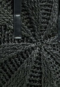 Borsa nera lavorata a maglia con un motivo testurizzato e dettagli intrecciati. Include due manici in pelle nera per il trasporto.