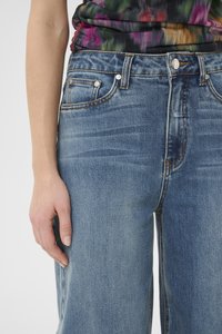 Light blue denim jeans featuring a straight cut, faded texture, five-pocket design, and contrast stitching. Closures include a button and zipper.