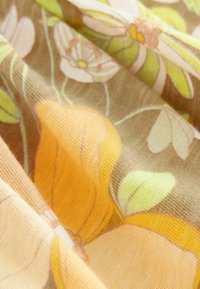 Stoff mit floralem Muster, gelben Blumen und grünen Blättern auf braunem Hintergrund. Weiches, leichtes Material mit glatter Textur.