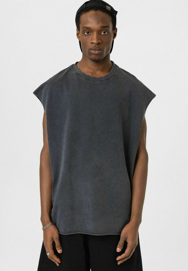 Donkergrijze mouwloze oversized T-shirt met een zachte textuur, ronde halslijn en minimale stikseldetails. Unieke, relaxte pasvorm.
