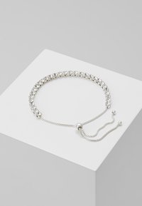 Silver adjustable bracelet with clear crystals set in a circular pattern, featuring a sliding bead closure and two chain accents.