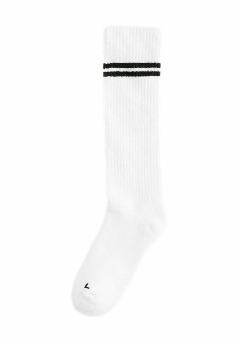 Chaussette blanche montante avec texture côtelée, présentant deux rayures noires horizontales en haut et un petit "L" imprimé sur le bout.