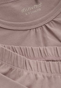 Helles rosa Kinderbekleidung mit gerafften Details, weichem Baumwollmaterial und einem Etikett, das die Größe 116 (6 Jahre) von Minymo angibt.