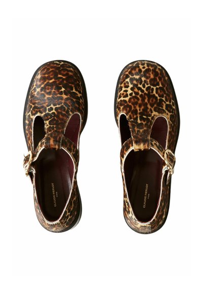 Une paire de chaussures Mary Jane à bout fermé en imprimé léopard, avec des boucles dorées et des semelles intérieures marron foncé, vues du dessus sur un fond blanc.