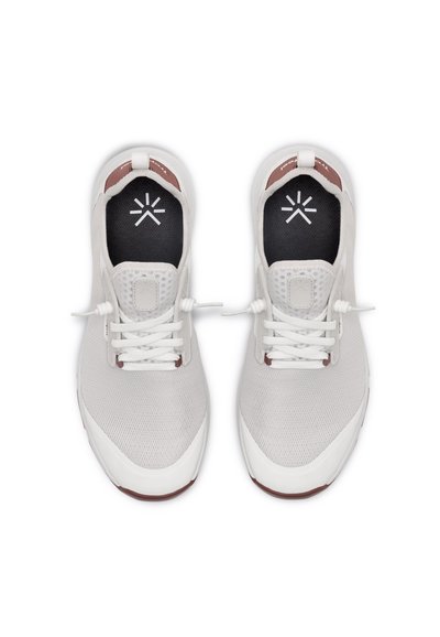 Chaussures de sport blanches avec dessus en mesh, design sans lacets, col rembourré, et semelle intérieure noire avec un logo. Semelle en caoutchouc avec des accents rouges.
