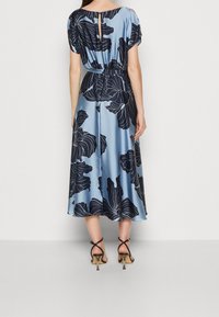Robe midi en soie bleu clair avec imprimé floral et motifs de fleurs navy. Taille élastique, manches courtes et détail en trou de serrure au dos. Sandales à talons.