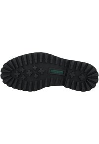 Semelle de chaussure en caoutchouc noir avec un motif texturé et cranté, comprenant des sections surélevées variées et une étiquette verte au centre.