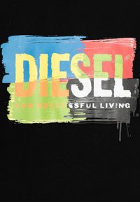 Černá textilie s barevnými štětcovými tahy obsahuje slovo "DIESEL" velkými bílými písmeny a "PRO ÚSPĚŠNÝ ŽIVOT" menším bílým textem pod ním.