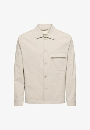 Helebeežikas puuvillane jakk, millel on terav kaelus, esiklõpsud ja rinnatasku. Sile tekstuur ja pikad varrukad.