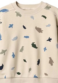 Sweat-shirt beige présentant un mélange de silhouettes d'animaux en bleu, vert et marron dans un motif dispersé, avec un col et des poignets côtelés.